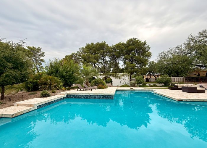 Lush backyard pool area with clear blue water, surrounded by greenery and lounge chairs, reflecting Luna Pool Service's commitment to quality pool maintenance and care in Tucson.